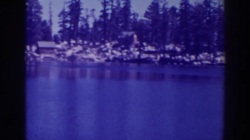Vintage Angora Lakes frame showing blue-toned water, pine trees and rustic cabins along the far shore.