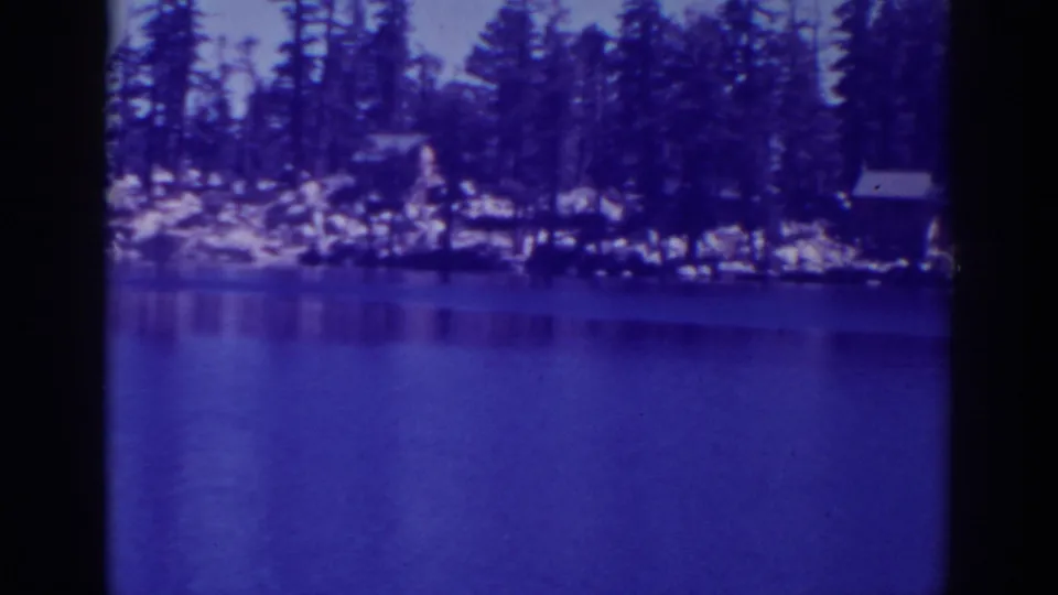 Final 8mm still of Angora Lakes with calm foreground water, distant pines, rocks and small cabins.
