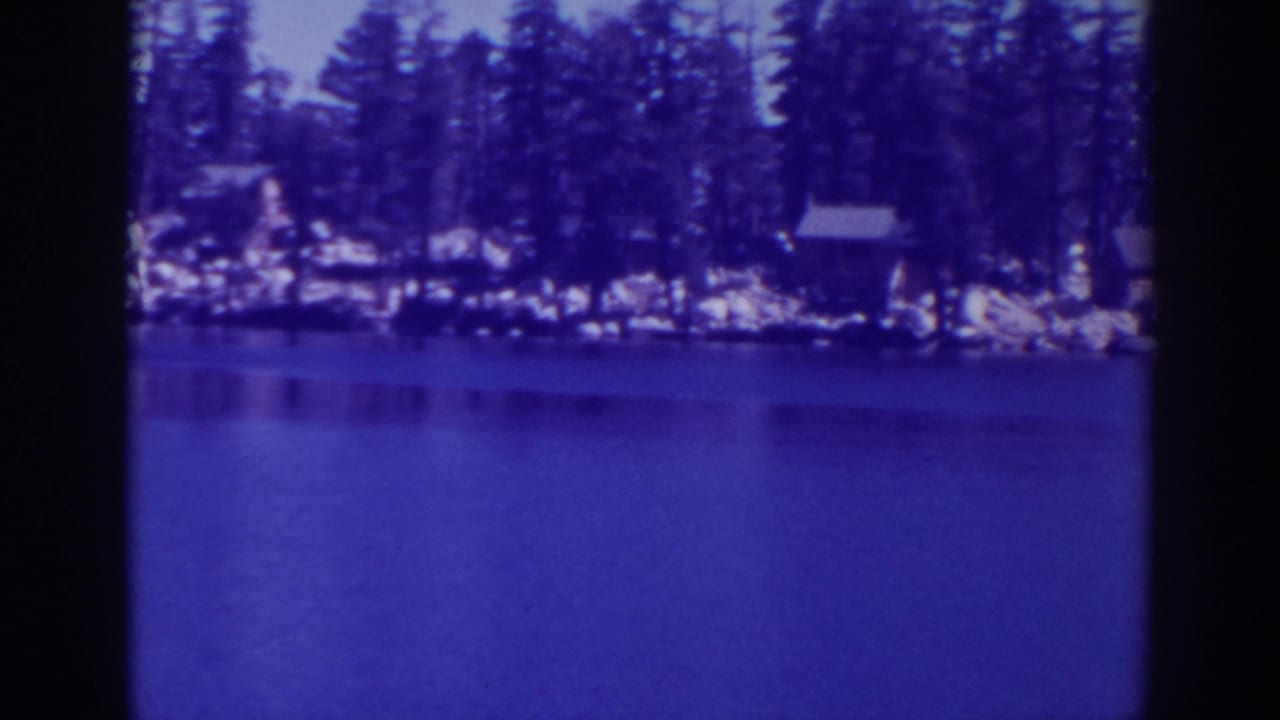 Lake and wooded shoreline seen through dark vertical film-frame borders.