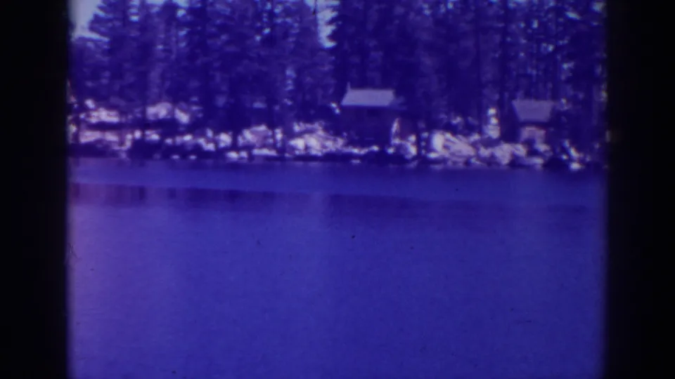 1938 home-movie view of Lower Angora Lake with a wooded rocky shoreline and small cabins across the water.