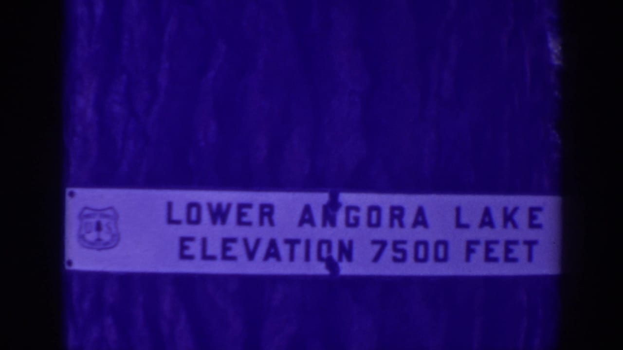 Close 1938 view of the Lower Angora Lake elevation sign, softened by aged 8mm color and gate shadows.