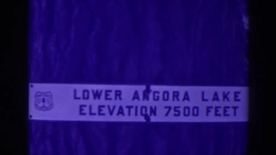 Close 1938 view of the Lower Angora Lake elevation sign, softened by aged 8mm color and gate shadows.