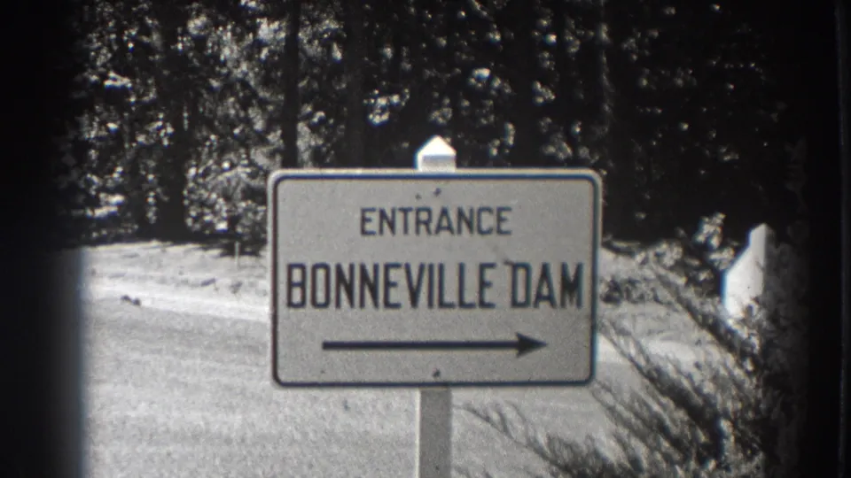 1938 Bonneville Dam entrance sign in Oregon, filmed beside a forest road with a right-pointing arrow.