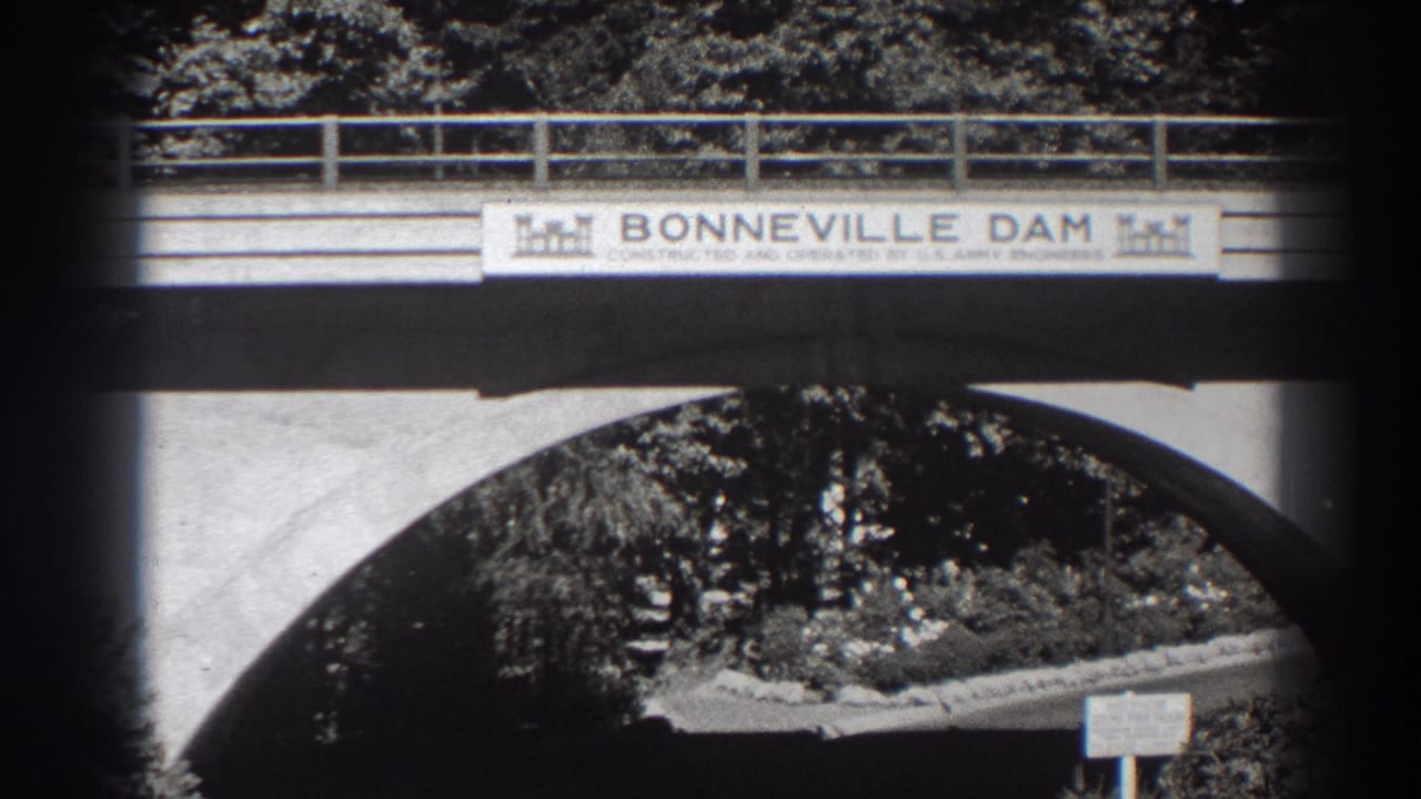 Bonneville Dam sign mounted on a bridge above a concrete arch and trees.