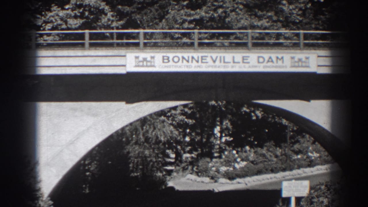 Bridge-mounted Bonneville Dam sign above a concrete arch and tree-lined entrance.