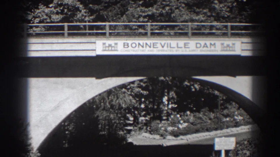 Final 1938 frame holds on the Bonneville Dam entrance sign and bridge arch, with dense trees and a small signboard in the lower right.