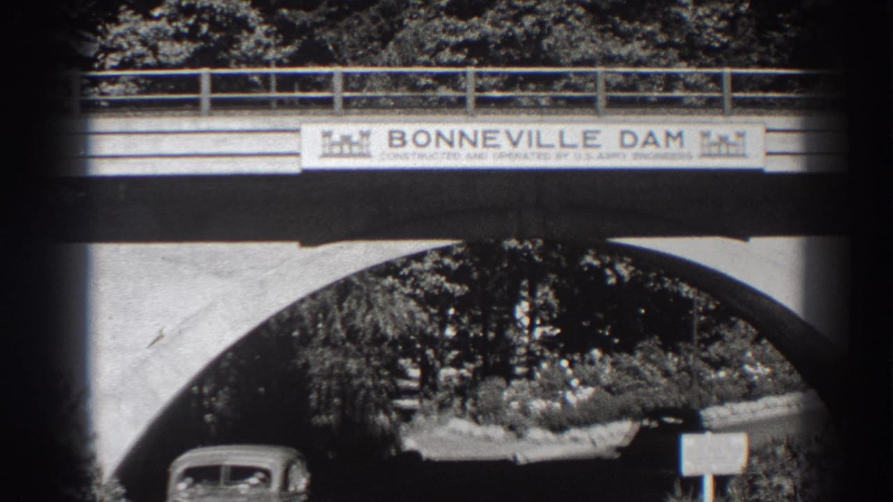 A car enters beneath the Bonneville Dam bridge sign and arch.