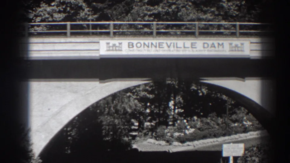 Final frame holds on the Bonneville Dam bridge sign and arched concrete opening, with trees behind and no visible people.