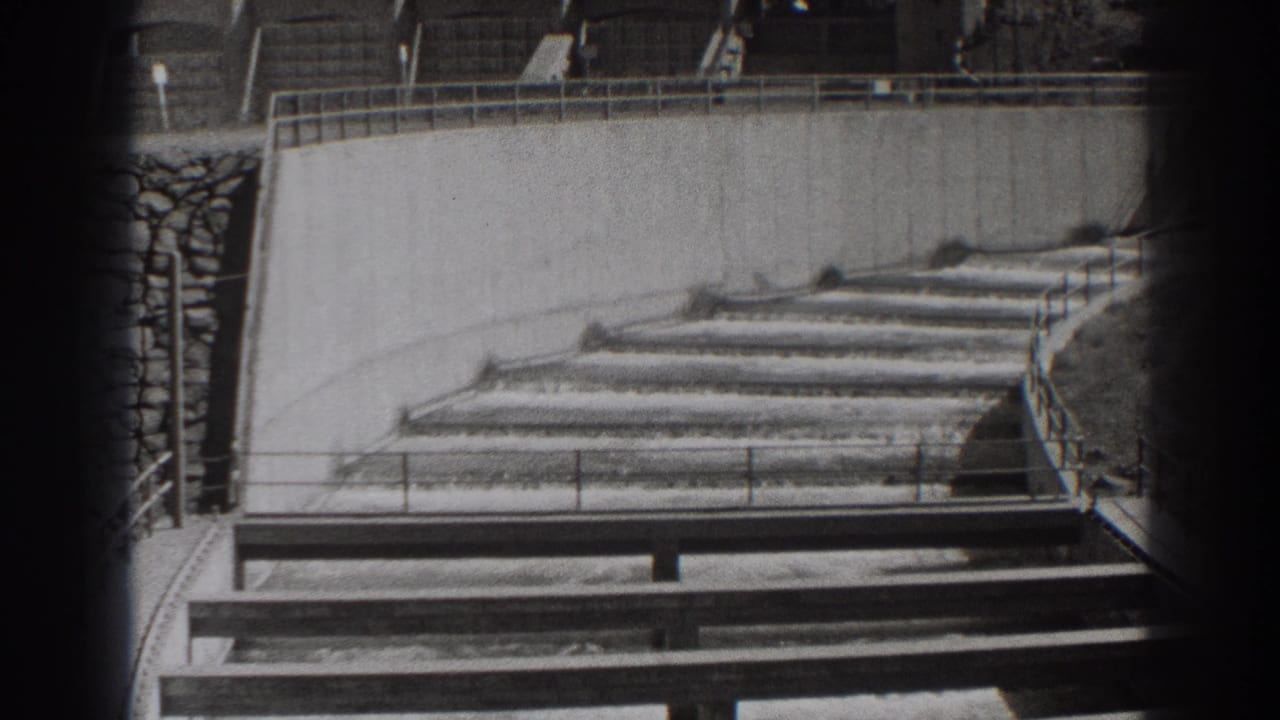 Stepped concrete water channel with railings and dark film-frame edges.