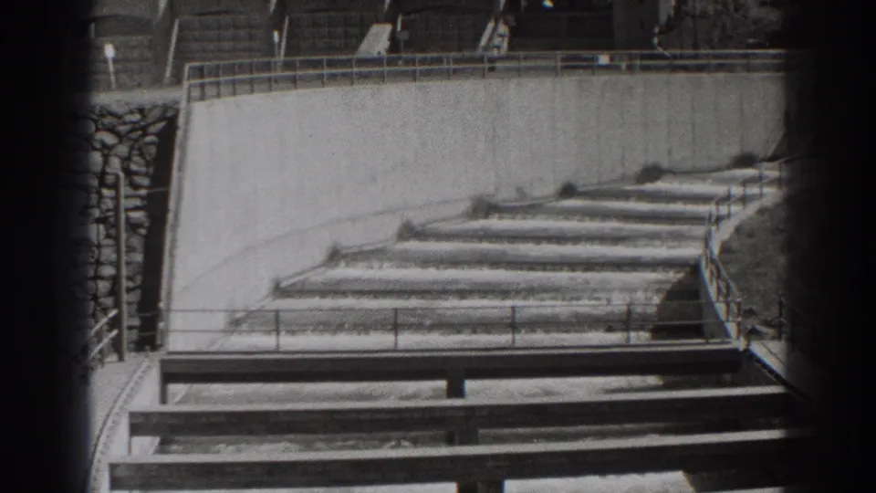 1938 Bonneville Dam view of water passing through stepped concrete weirs, framed by railings and heavy 8mm vignette.