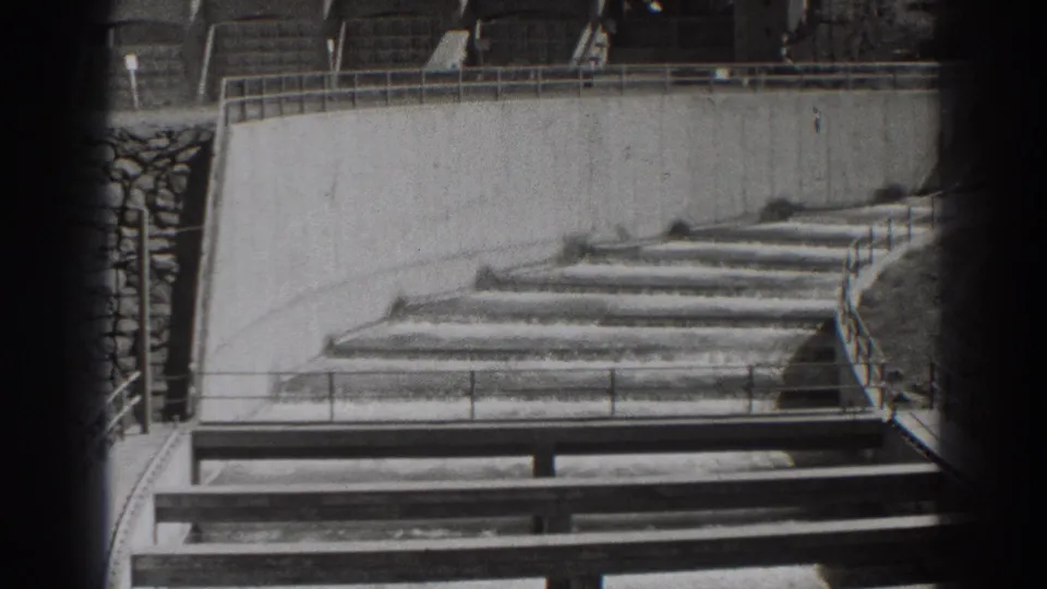 Bonneville Dam concrete water channel in 1938, showing shallow flow over stepped weirs beside railings and a retaining wall.