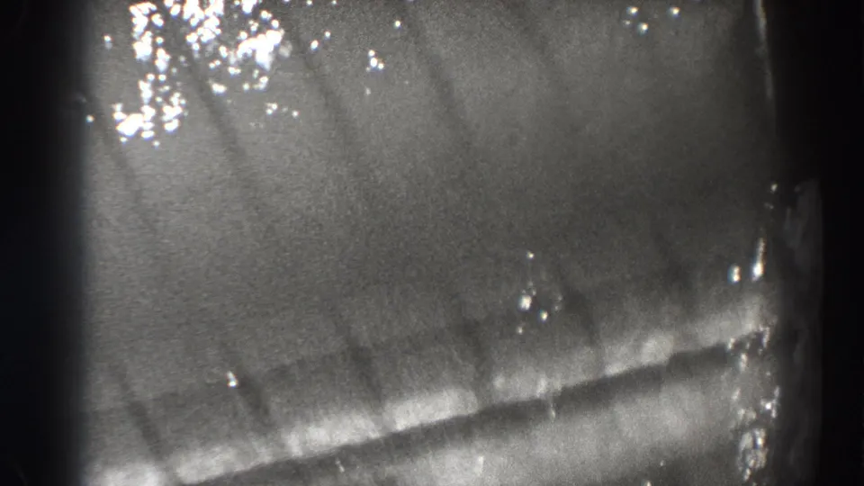 Final 1938 Bonneville Dam frame with rippling current, bright specks, and a subdued fish silhouette near the lower waterline.