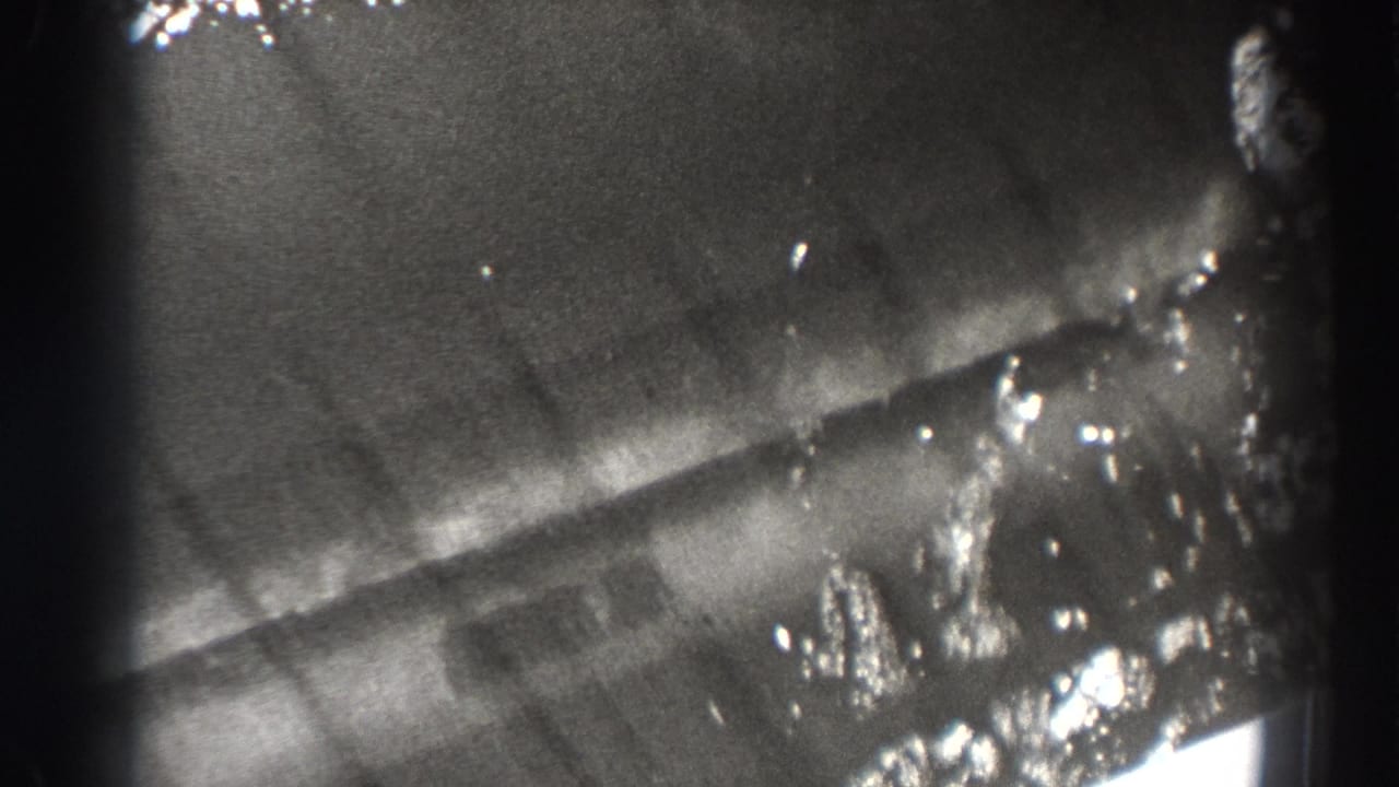Soft black-and-white view of water or structural surface with bright reflections near the frame edge.