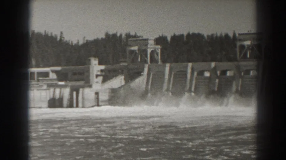 1938 8mm view of Bonneville Dam in Oregon, showing water pouring from the spillway into a churning river below.
