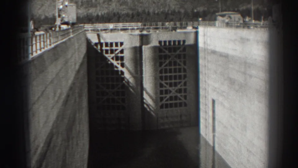 1938 Bonneville Dam footage showing a concrete wall, gridded gate structures, railings, and dark water inside the dam channel.