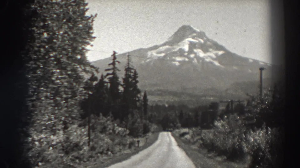 1938 Bonneville Dam area home-movie view of a road leading through trees toward a distant snow-marked mountain.