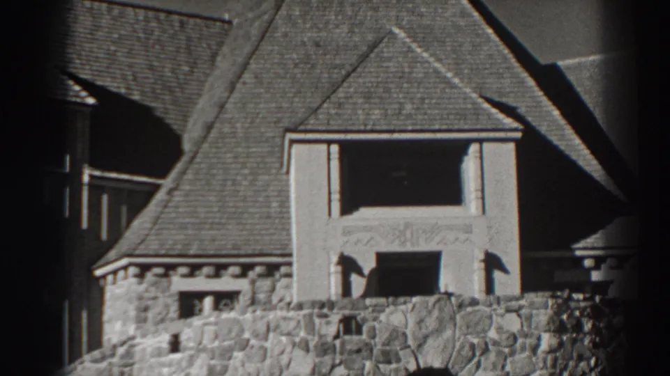 1938 Bonneville Dam area view of a stone public building facade with steep rooflines and a shadowed arched doorway.