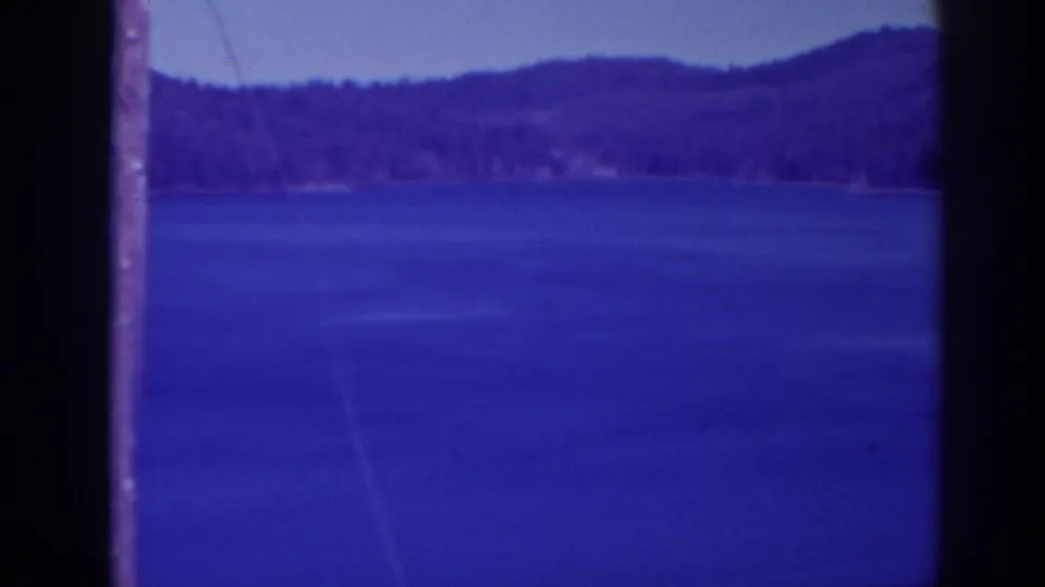 1938 Bucks Lake home-movie frame showing open water, a distant tree-covered shoreline, low hills, and visible 8mm frame boundaries.