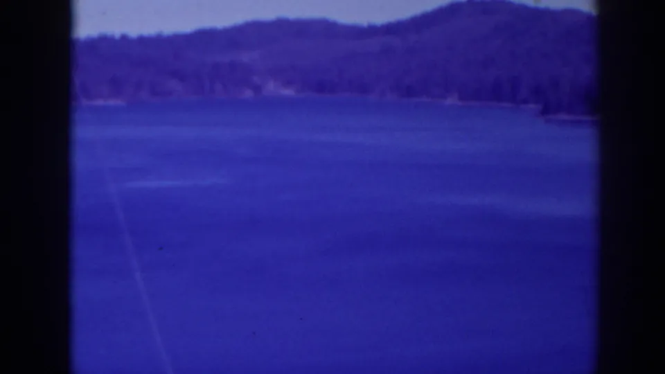1938 Bucks Lake frame showing a wide blue lake, distant forested hills, shoreline detail, and strong dark borders from the film scan.
