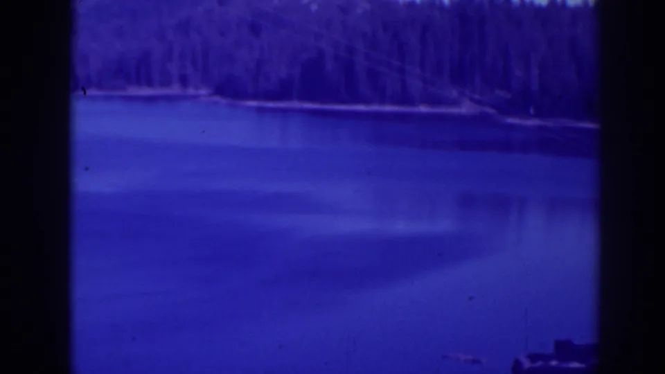 Bucks Lake frame with calm water, forested shore, blue-purple tint, and a small dock or boat-like shape near the right edge.