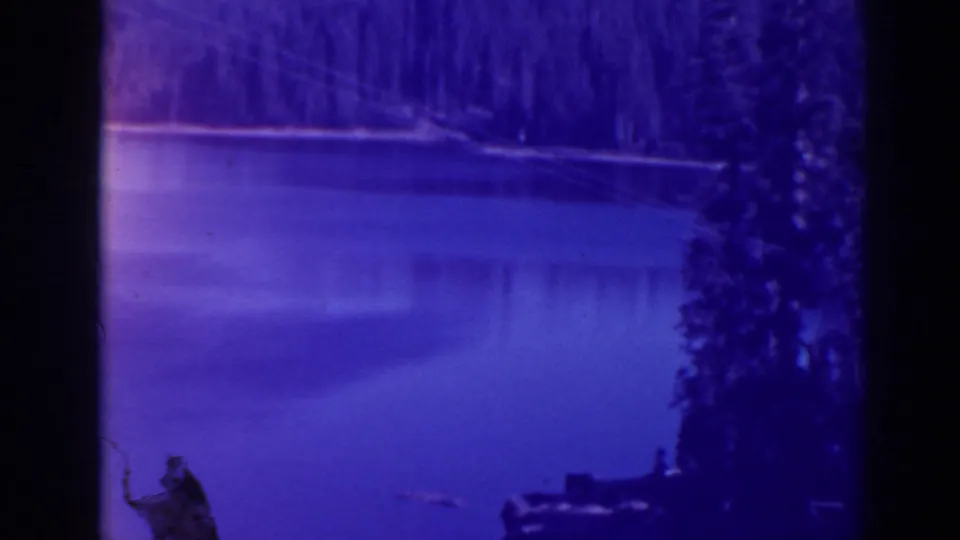 Bucks Lake, California frame showing calm water, a wooded shoreline, film gate bars, and a small dock or boat-like form near shore.
