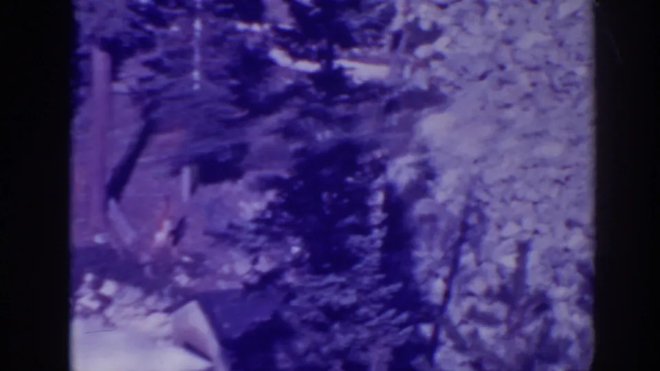 Late frame from 1938 Bucks Lake footage with a blurred water jet against rocks, trees, and pronounced home-movie color shift.
