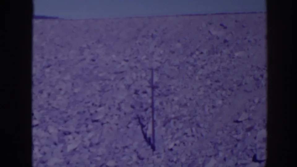 1938 Bucks Lake area 8mm frame showing rocky empty terrain, pale sky, and a single utility pole within dark film-frame edges.