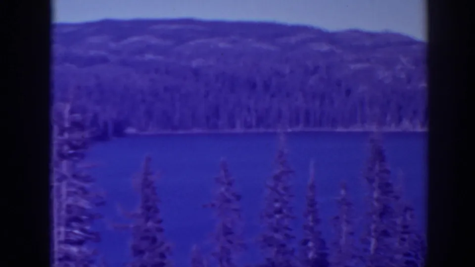 1938 Bucks Lake view with blue water, evergreen shoreline, wooded hills, and clear sky in color 8mm footage.
