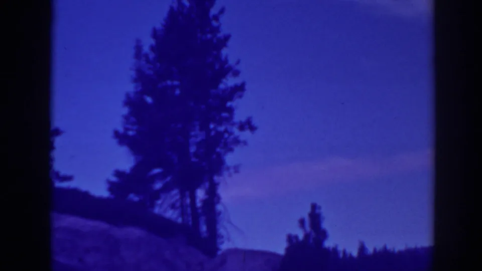 Bucks Lake, California frame with dark conifers, low terrain, and saturated twilight color from 8mm film.