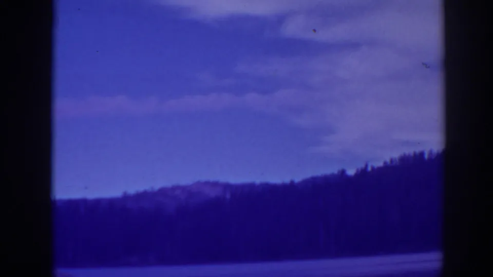 Bucks Lake landscape frame showing water or open shoreline, dark forested hills, and a purple-blue sky.