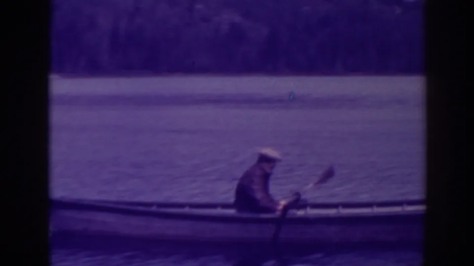 The final frame shows the man seated in the rowboat on Bucks Lake, holding the oar as the aged 8mm image darkens around the gate edges.