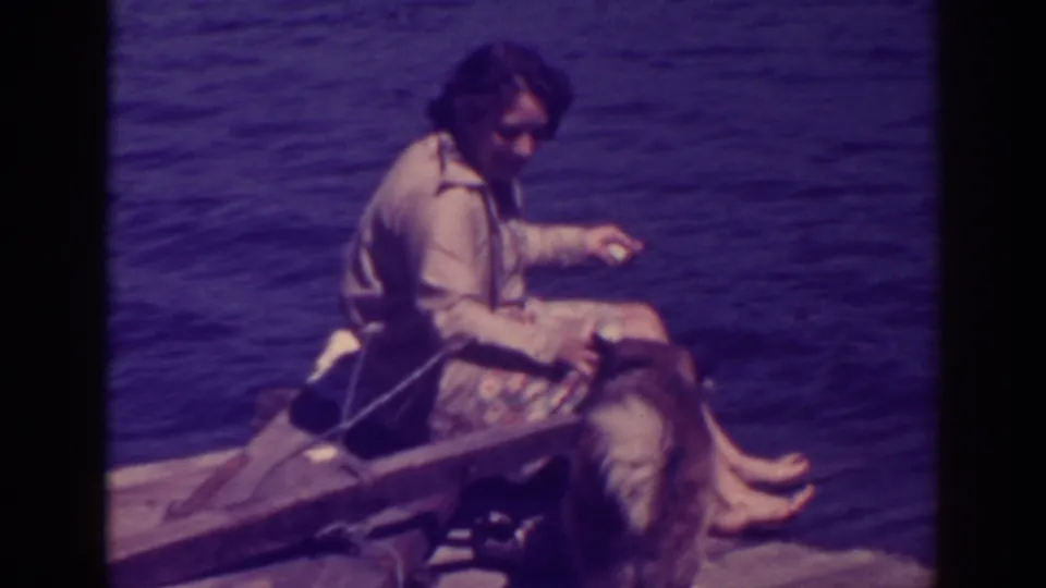 At Bucks Lake in 1938, a woman sits barefoot on a wooden raft while a large dog rests or stands close beside her.