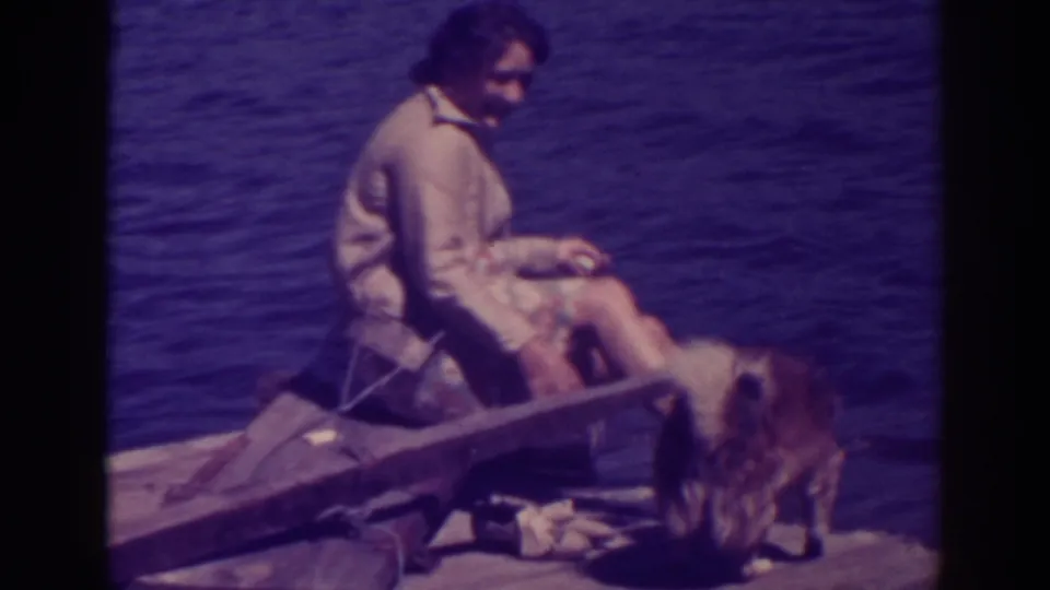 At Bucks Lake in 1938, the woman sits on the wooden raft and glances toward the camera while the dog stands near her legs.