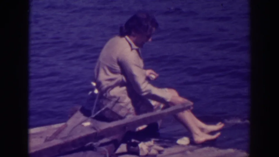 At Bucks Lake in 1938, the woman sits sideways on the rough raft, barefoot, as the dog is mostly out of frame near the lower edge.