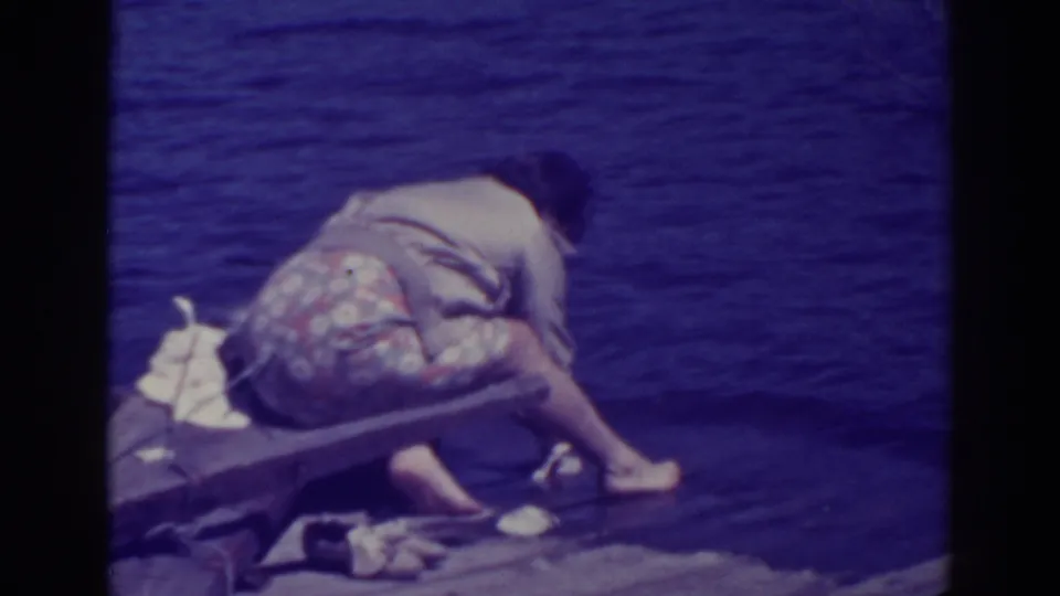 Near the end of the clip, the woman crouches over the Bucks Lake shoreline, reaching down toward the water with laundry beside her.