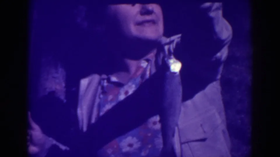 In 1938 Bucks Lake footage, a woman in a light jacket holds up a fishing rod with a fish hanging near her shoulder.