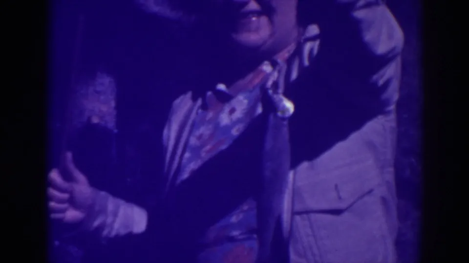 The woman smiles while presenting a dangling fish on a rod in the dim 1938 Bucks Lake home-movie scene.