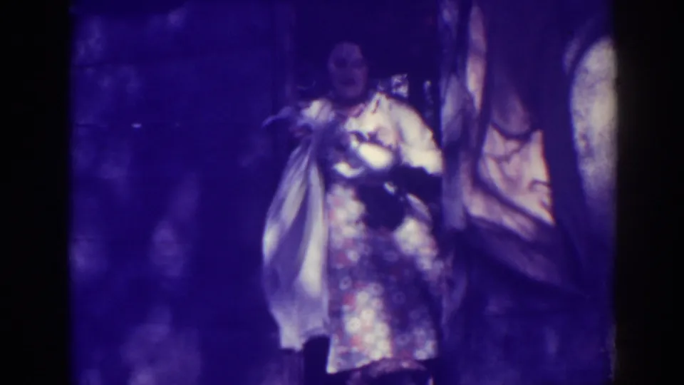 Near the end of the clip, the woman stands in a patterned dress and light jacket with the fish and gear visible beside her.