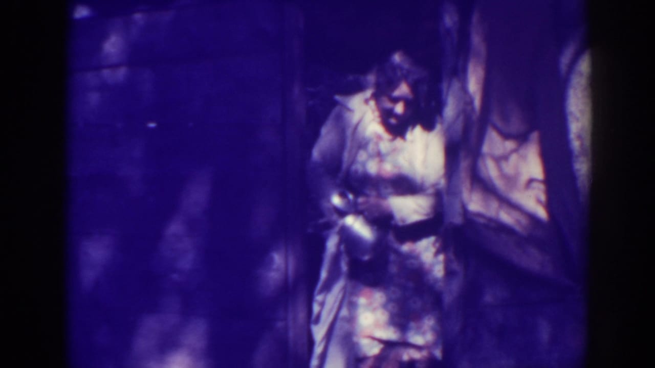 Person standing in a dark purple-tinted frame, holding or adjusting gear near a vertical surface.
