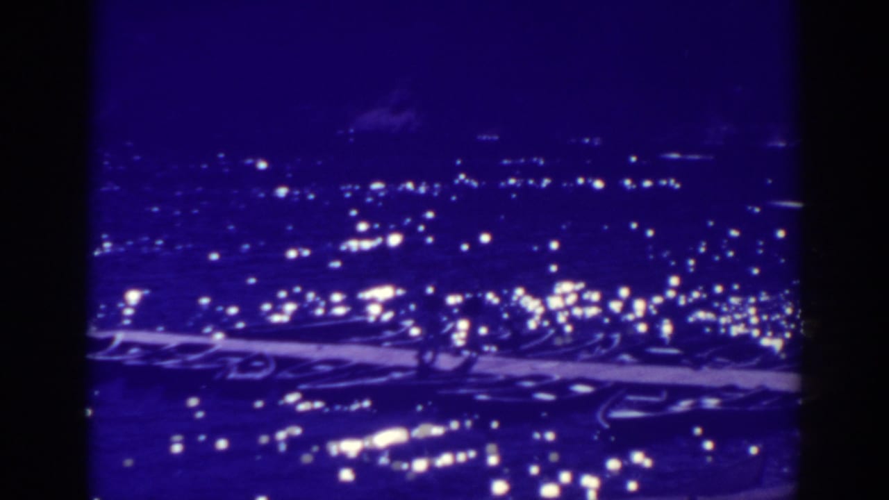 1938 Bucks Lake home-movie frame showing a dark lake or shoreline with scattered lights and a purple film cast.