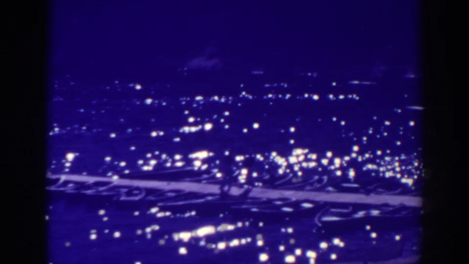 1938 Bucks Lake home-movie frame showing a dark lake or shoreline with scattered lights and a purple film cast.