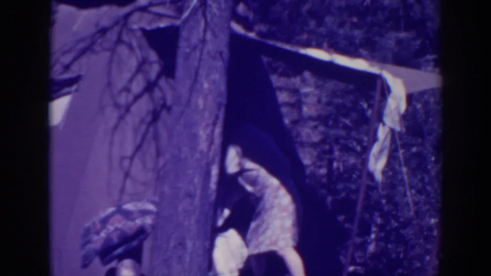 Near the end of the clip, the woman leans into the tent area, continuing to arrange laundry in the wooded Bucks Lake campsite.