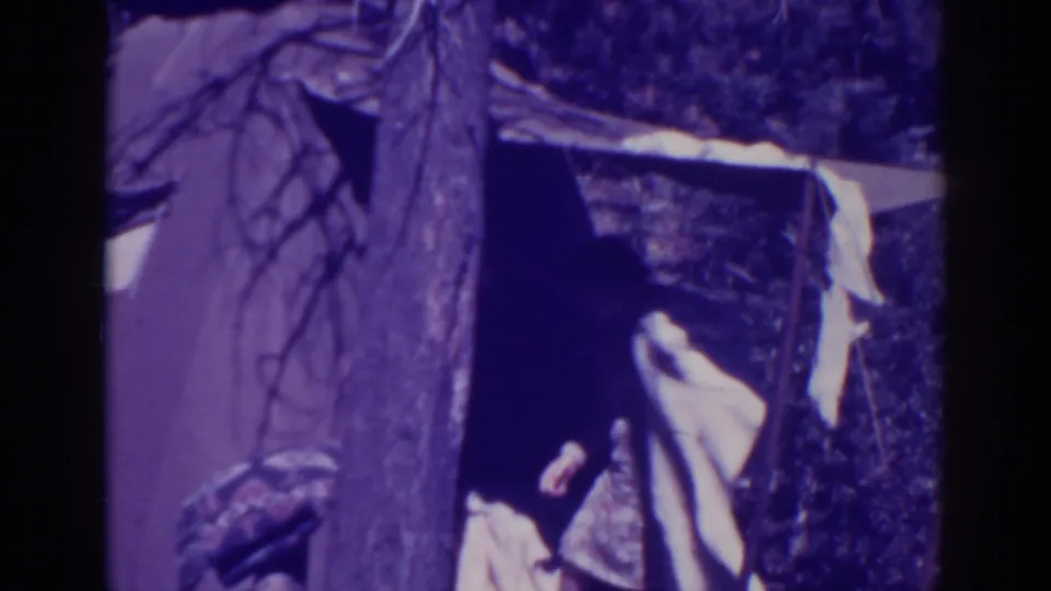 A person at the Bucks Lake camp moves near the tent opening while a light cloth hangs from a line.