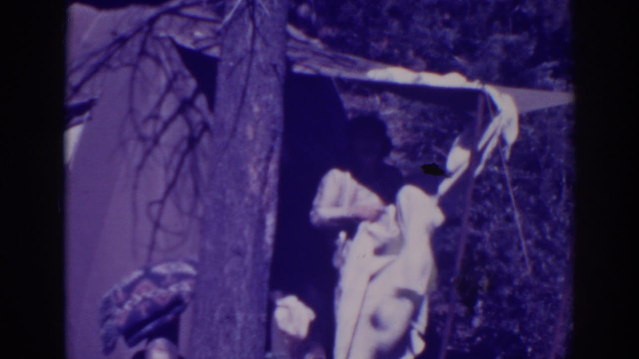 Woman reaches toward pale fabric at the tent entrance.