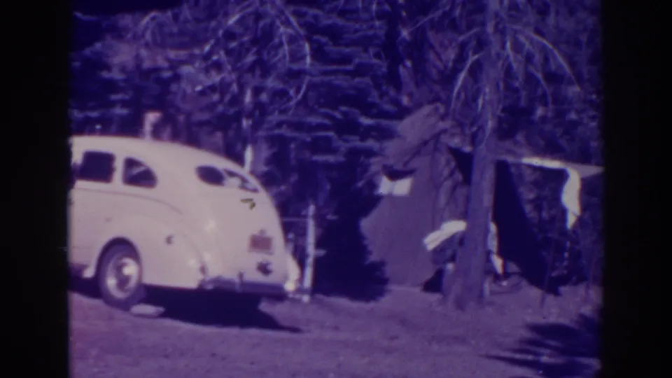 Bucks Lake 1938 frame with a white rounded sedan parked beside trees near the camping area.