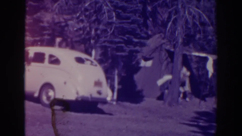 Bucks Lake 1938 campsite view with a white sedan, tree branches, and tent fabric visible nearby.