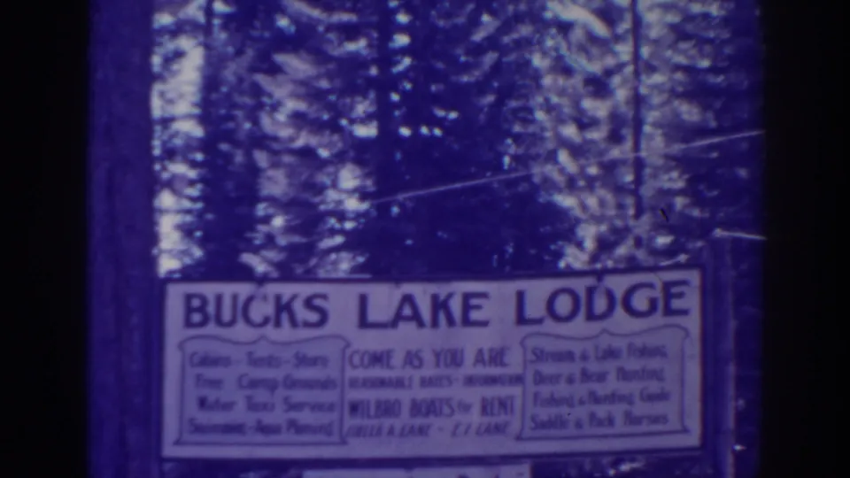 Bucks Lake Lodge sign in a wooded Bucks Lake, California setting, advertising cabins, boats, meals, and fishing services.