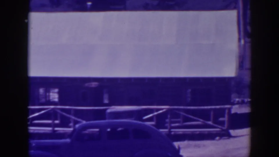 1938 Bucks Lake frame with a dark vintage car near a rustic building and a pale rectangular wall or sign area.