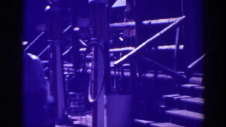 Blue-shifted 1938 Bucks Lake home-movie frame showing a close lakeside structure or boat detail with railings, steps, and deep shadow.