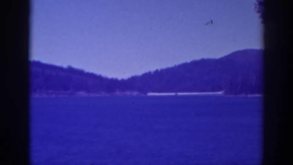 1938 Bucks Lake home-movie frame showing blue water, distant wooded hills, twilight sky, and visible film gate edges.